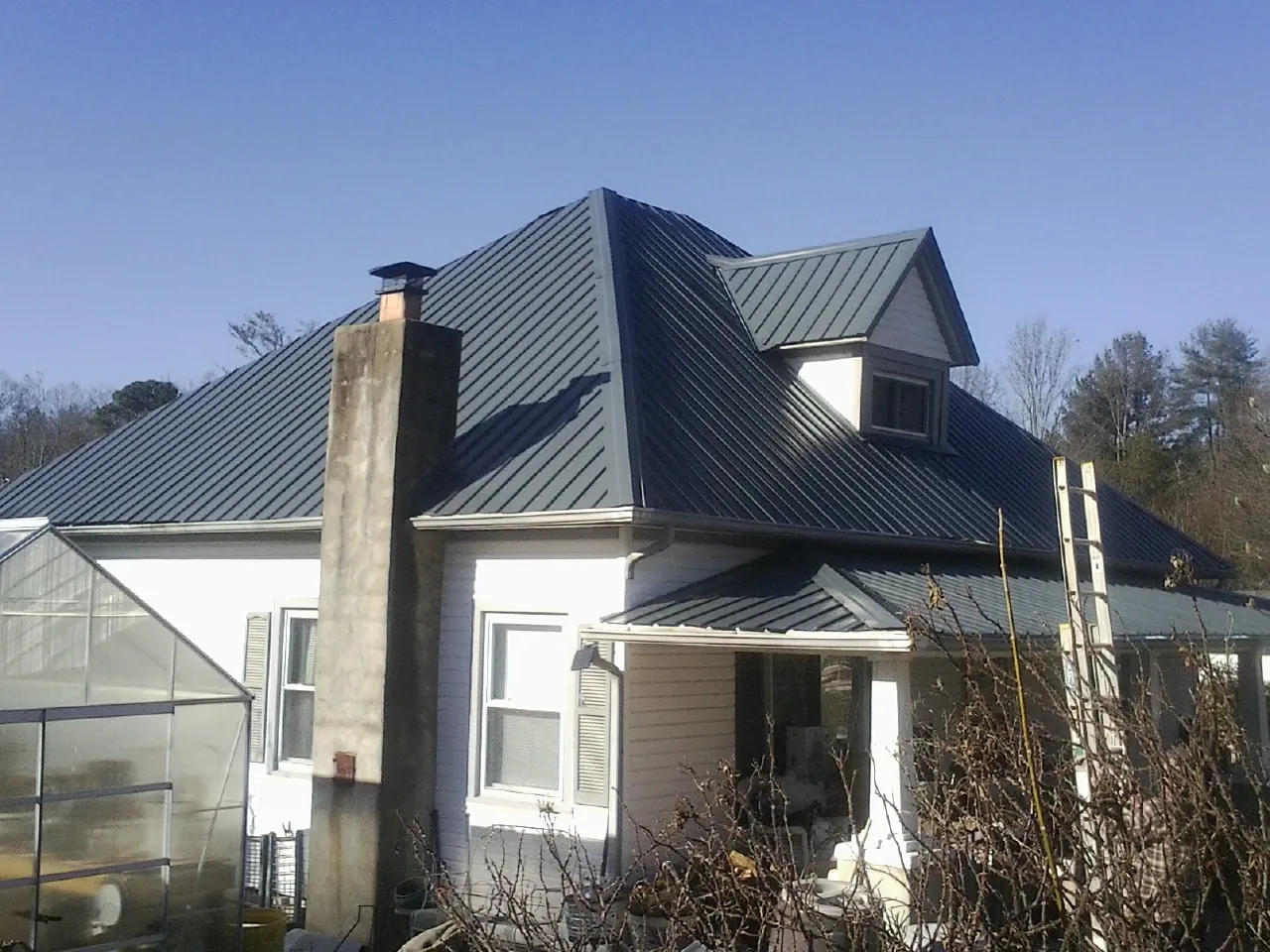 Dark blue standing seam metal roof on a white farmhouse with dormer — Slate & Tile Roof Repair by Roofing Brothers in Altamont