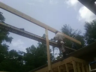 Carpenter setting a ridge beam over a new addition frame in Altamont