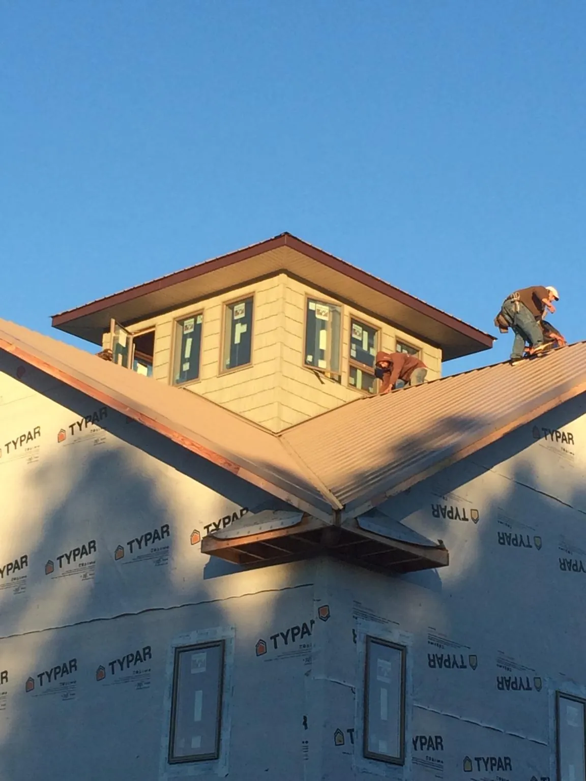 Roofers working around a rooftop cupola on a new metal roof at sunset — Roof Waterproofing in Altamont by Roofing Brothers